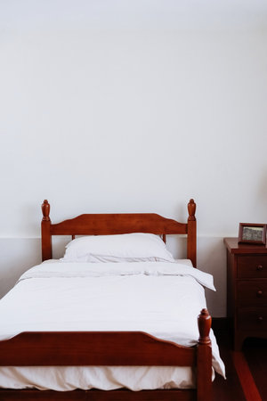 image of Wooden bed and furniture in a hotel room with white sheets and pillows, vintage bed room decorの写真素材