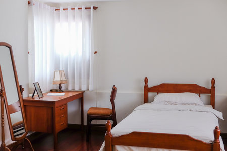 image of Wooden bed and furniture in a hotel room with white sheets and pillows, vintage bed room decorの写真素材