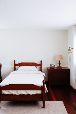 image of Wooden bed and furniture in a hotel room with white sheets and pillows, vintage bed room decorの写真素材