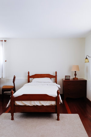 image of Wooden bed and furniture in a hotel room with white sheets and pillows, vintage bed room decorの写真素材