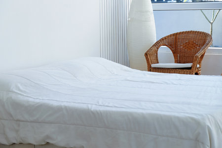 Interior of a modern bedroom with white bed and wicker chairの写真素材