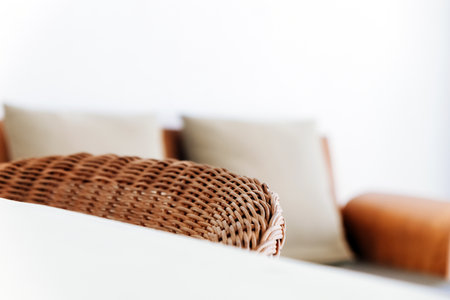 Close up of wicker chair and pillow on sofa in living roomの写真素材