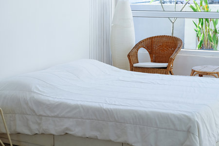 Interior of a modern bedroom with white bed and wicker chairの写真素材