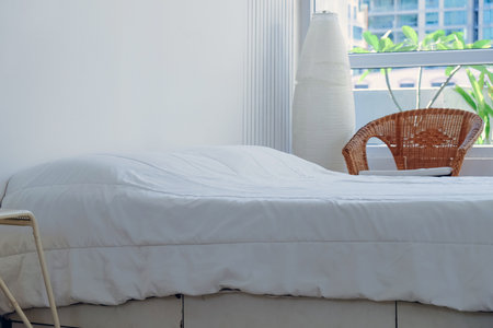 Interior of a modern bedroom with white bed and wicker chairの写真素材