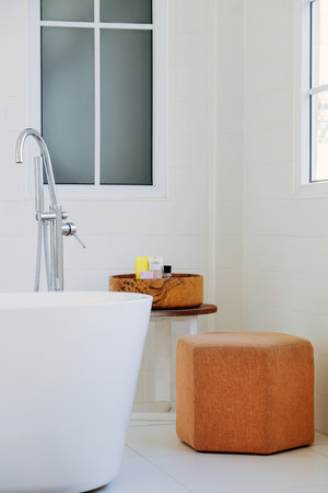 interior of modern bathroom with white bathtub and brown stoolの写真素材