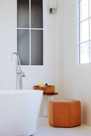 interior of modern bathroom with white bathtub and brown stoolの写真素材
