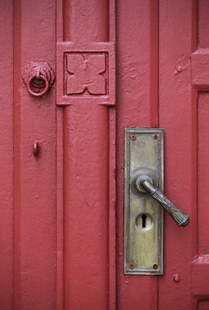 Door handle with an old double wood door painted red colorの写真素材