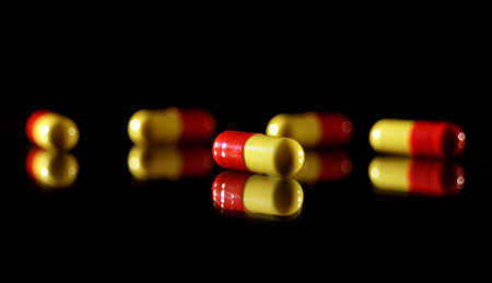 Pills on crisp black background with reflectionの写真素材