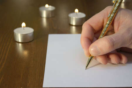 Hand wiriting with golden pen with candlesの写真素材