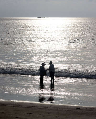 Fishermen by the ocean in sunsetの写真素材
