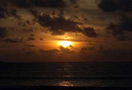 Beautiful dark sunset over the ocean with cloudsの写真素材