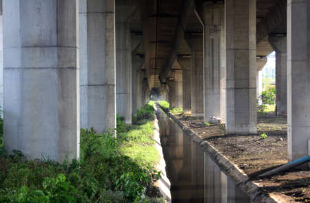 Tunnel under freeway with concrete pillars with sun shining through
