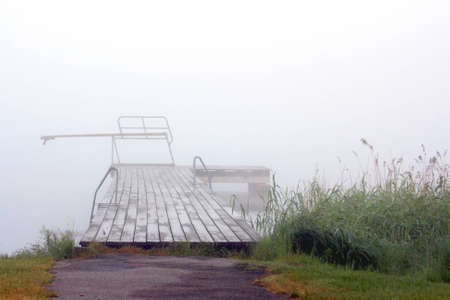 Misty morning by the river with reed and pierの写真素材