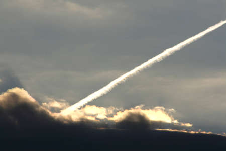 Plane track or rocket launch through the cloudsの写真素材