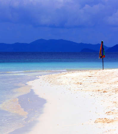Parasol on a deserted beach with mountains in the backgroundの写真素材