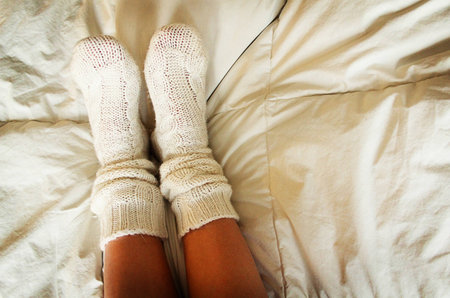 Knitted socks in bed on cozy coverの写真素材