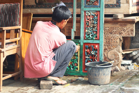 Man renovating wooden colourful door, sitting downの写真素材