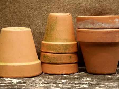row of stacked terra cotta flower pots with olive green backgroundの写真素材