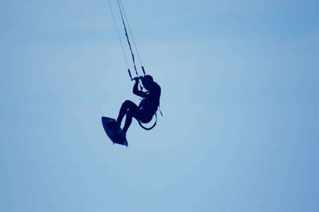 kitesurfing, silhouette of sportmen on blue