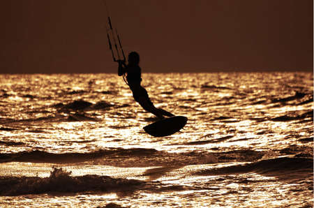 silhouette of flying kitesurfer 