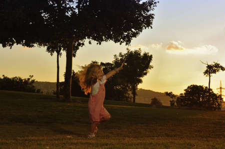 Portrait of cute young girl running on lawn at dawnの写真素材