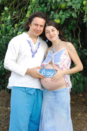 Young happy pregnant woman and  her husband in the country clothesの写真素材