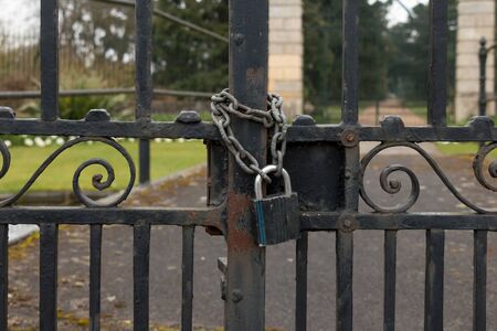 A Lock and Chain on Metal Fence Gate to the Roadの写真素材