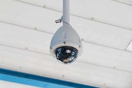 Round CCTV Camera hanging on White Ceilingの写真素材