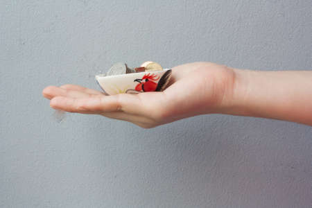 hands holding coins in heart shape ceramic containerの写真素材