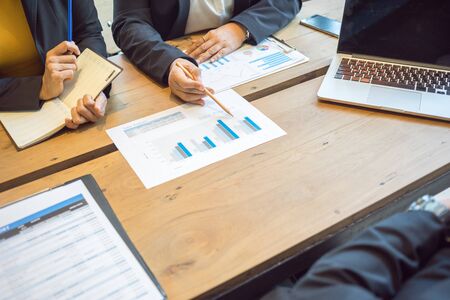 Female employees are explaining sales summary report to top management.