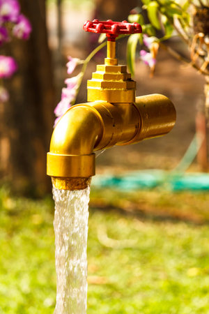 Old rusty water tap on cracked concrete wallの写真素材