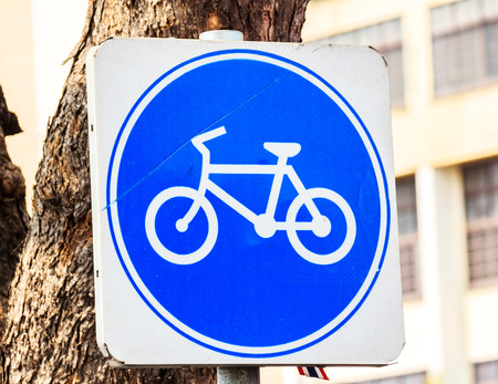 round bicycle lane sign against a treeの写真素材