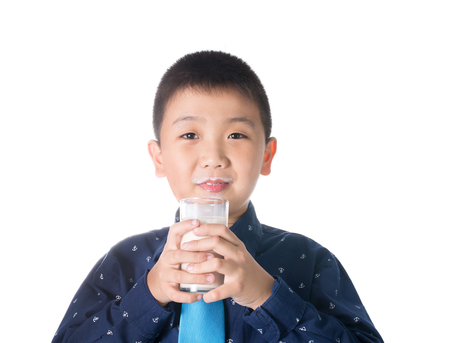 Boy  drinking milk with milk mustache holding glass of milk isolated on white background.の写真素材