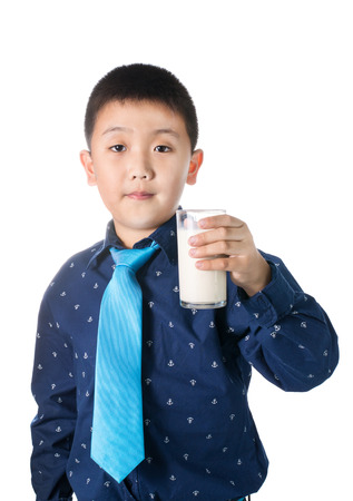 Happy boy with glass of milk in hand isolated on white background.の写真素材