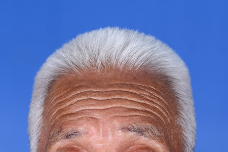 Close up of grey hair on top of elderly man head wrinkle tan skin.の写真素材