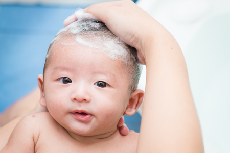 Mother give a bath her newborn baby in bathroom, focus at the eyeの写真素材