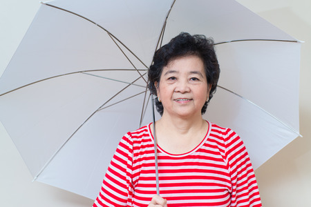 Good healthy asian woman smiling and holding white umbrella in studio shot, specialty tones with soft shadowの写真素材