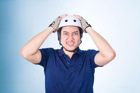 Asian guy with bicycle helmet and gloves, on blue backgroundの写真素材