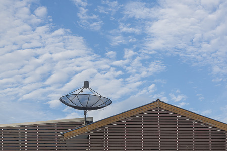 Big Black Satellite Dish on the roof with blue sky and cloudの写真素材