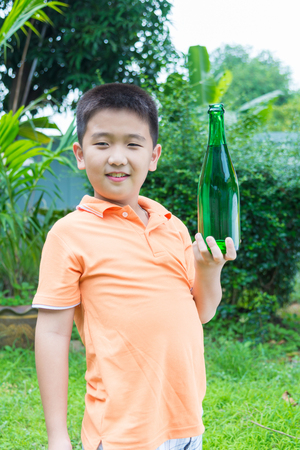 Asian boy drinking water from green bottle, in gardenの写真素材