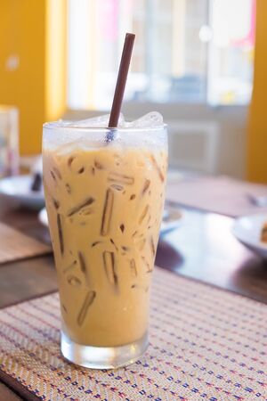 A glass of iced coffee with milk is on the mat, in coffee shop, Shallow DOFの写真素材