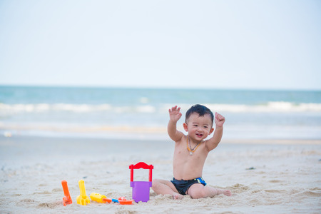 Little Asian boy 1 year old playing sand on the beach, in Thailandの写真素材