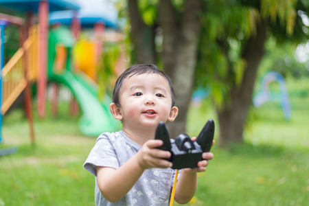 Little Asian kid holding a radio remote control (controlling handset) for helicopter , drone or...