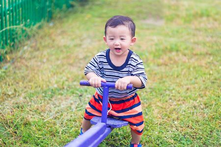 Happy kid play  teeter-totter in kindergarten or preschool, blue color tone, shallow DOF