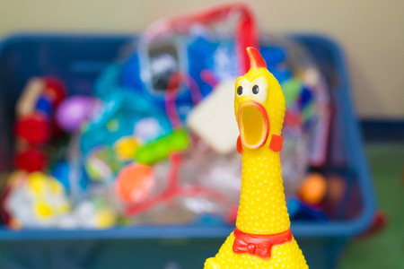 Toy rubber shriek yellow chicken on blur toy background in messy room, kid roomの写真素材