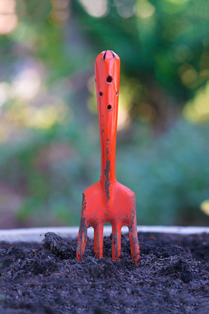 Orange fork harrows on black soil ground. background and texture, Earth day concept.の写真素材