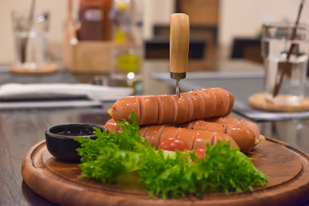Fried sausages with vegetable in wood plate. On the wooden table in dark room under Incandescent light. shallow focus.の写真素材