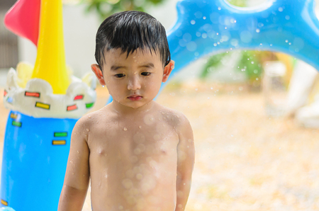Asian kid playing in inflatable baby pool. Boy swim and splash in colorful swimming pool with water toys on hot summer day. shallow focusの写真素材