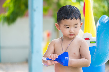Asian kid playing in inflatable baby pool. Boy swim and splash in colorful swimming pool with water toys on hot summer day. shallow focusの写真素材