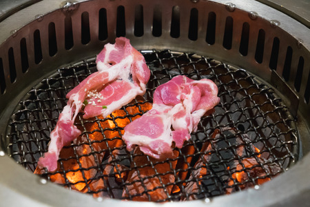 Raw pork slice for barbecue Japanese style yakiniku. roast pork on hot grill with red charcoal. shallow focus.の写真素材